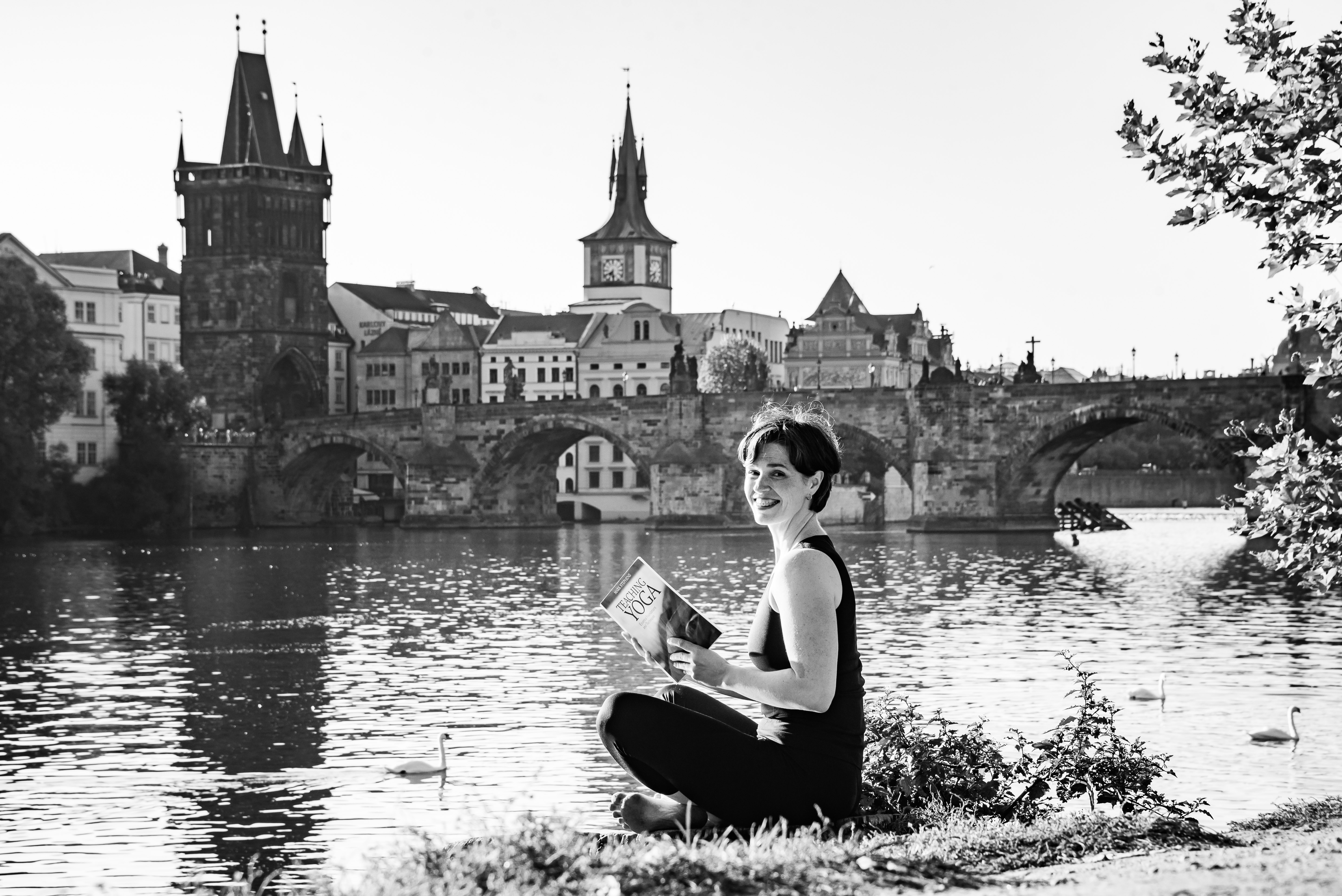 a woman sitting at the river, reading a book