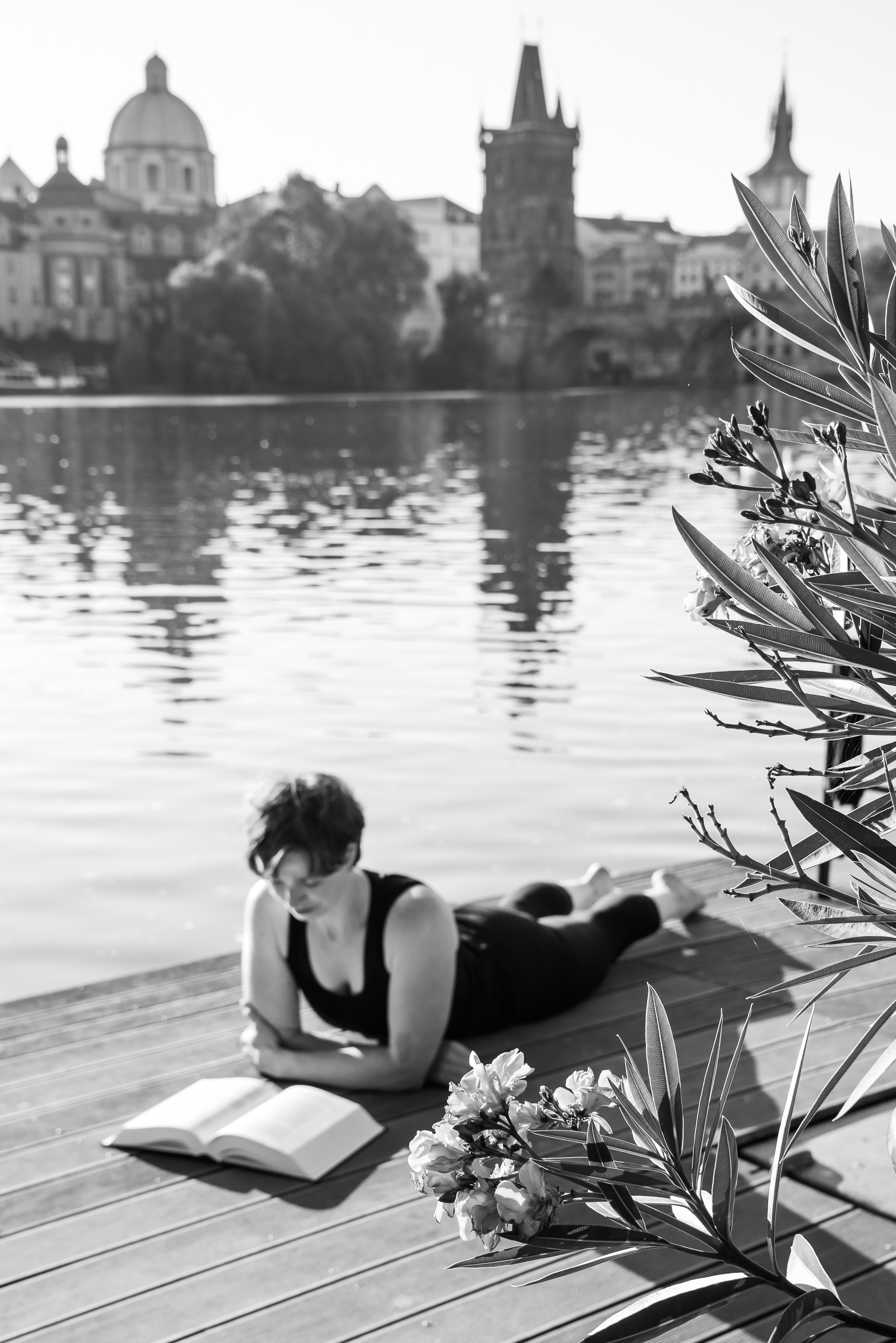 woman laying on the bank of the river reading a book